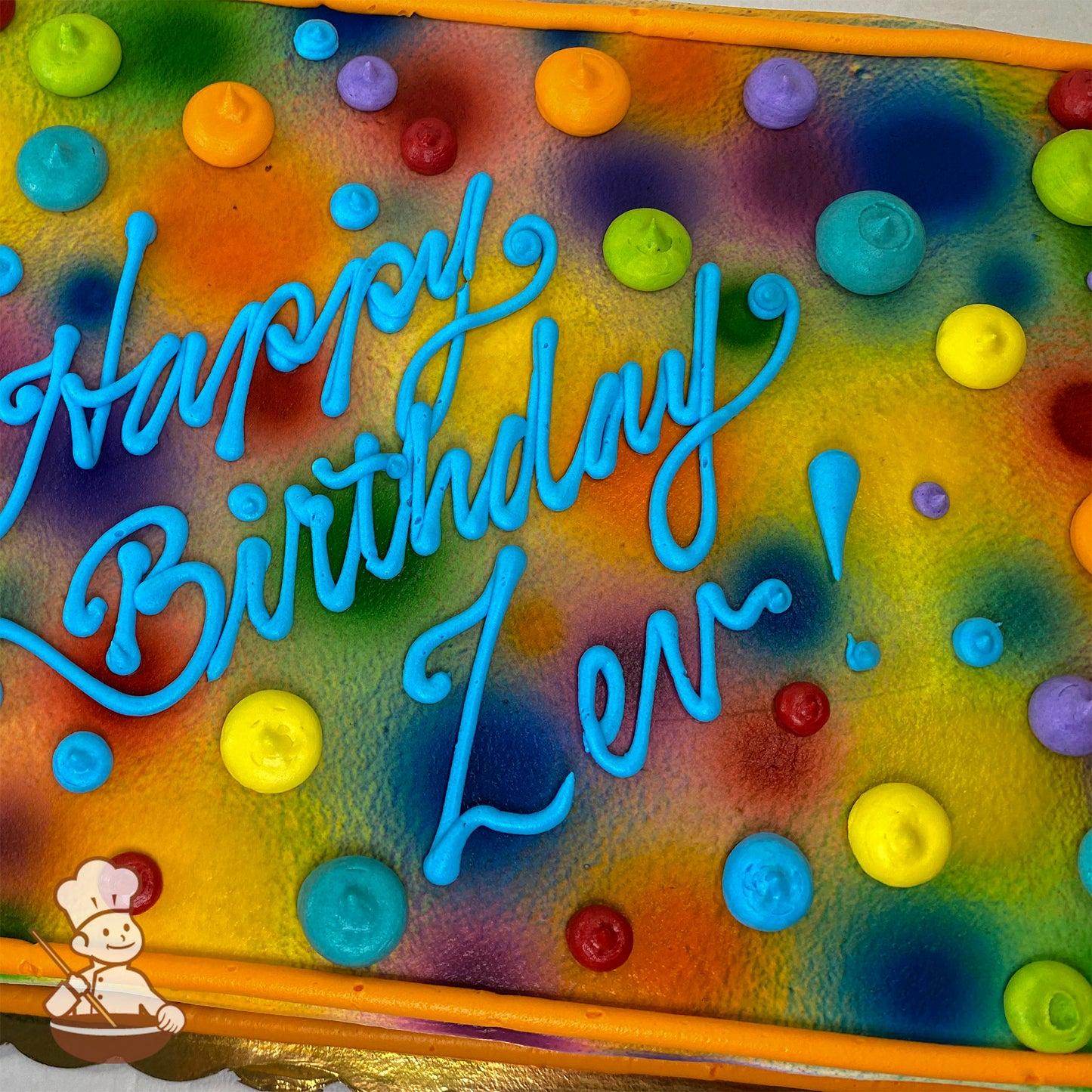 Colorful sheet cake with rainbow spray background, dotted with vibrant buttercream dots in blue, yellow, red, green, and purple.