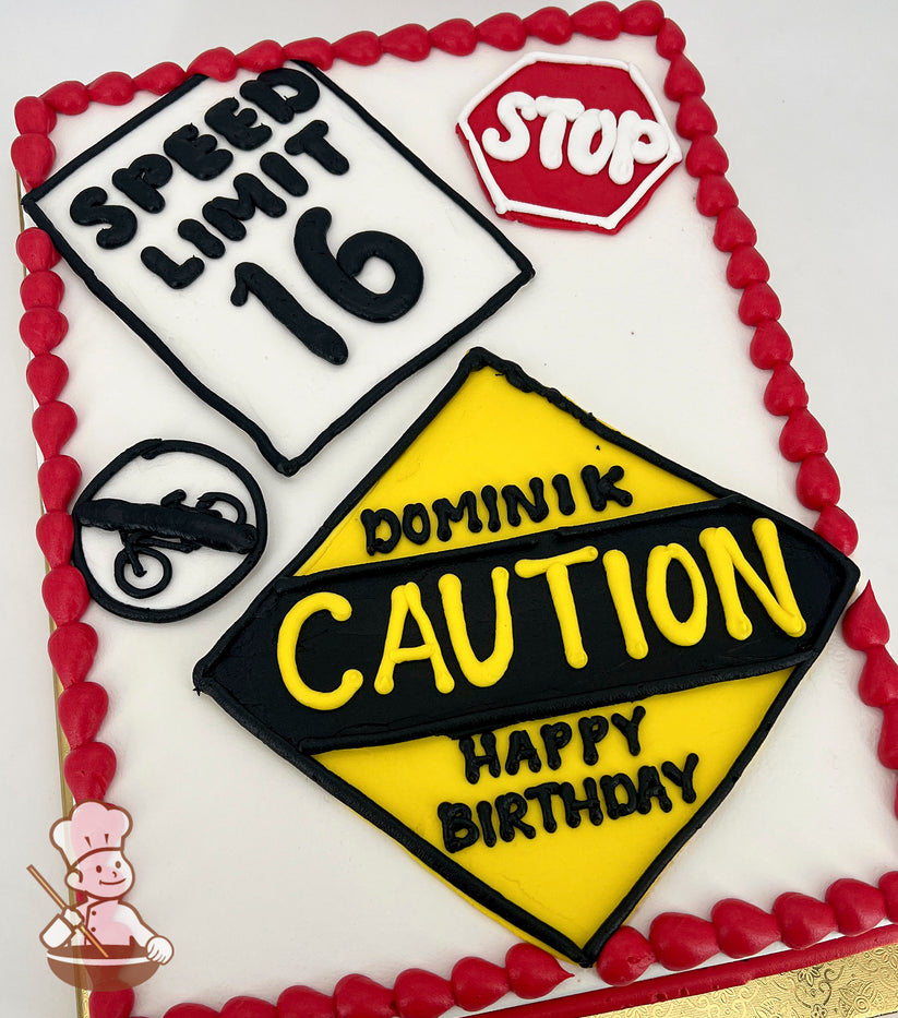 Sheet cake with buttercream road sign decorations, including a yellow caution sign, a red stop sign, a speed limit sign, and a no motorcycles sign. Red border.