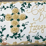 Sheet cake with buttercream decorations featuring a cross made of cream-colored roses and green leaves, surrounded by green vine designs and a cream border.