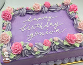 Purple sheet cake with pink and light pink buttercream roses, lavender swirl trim, and small sugar white pearls.