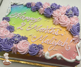 Sheet cake with a rainbow gradient background, decorated with pink and purple buttercream rosette swirls, white sprinkles, and piped white borders.