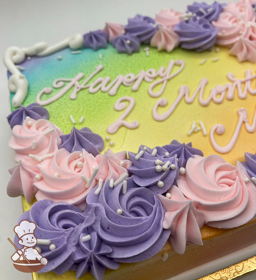 Sheet cake with a rainbow gradient background, decorated with pink and purple buttercream rosette swirls, white sprinkles, and piped white borders.