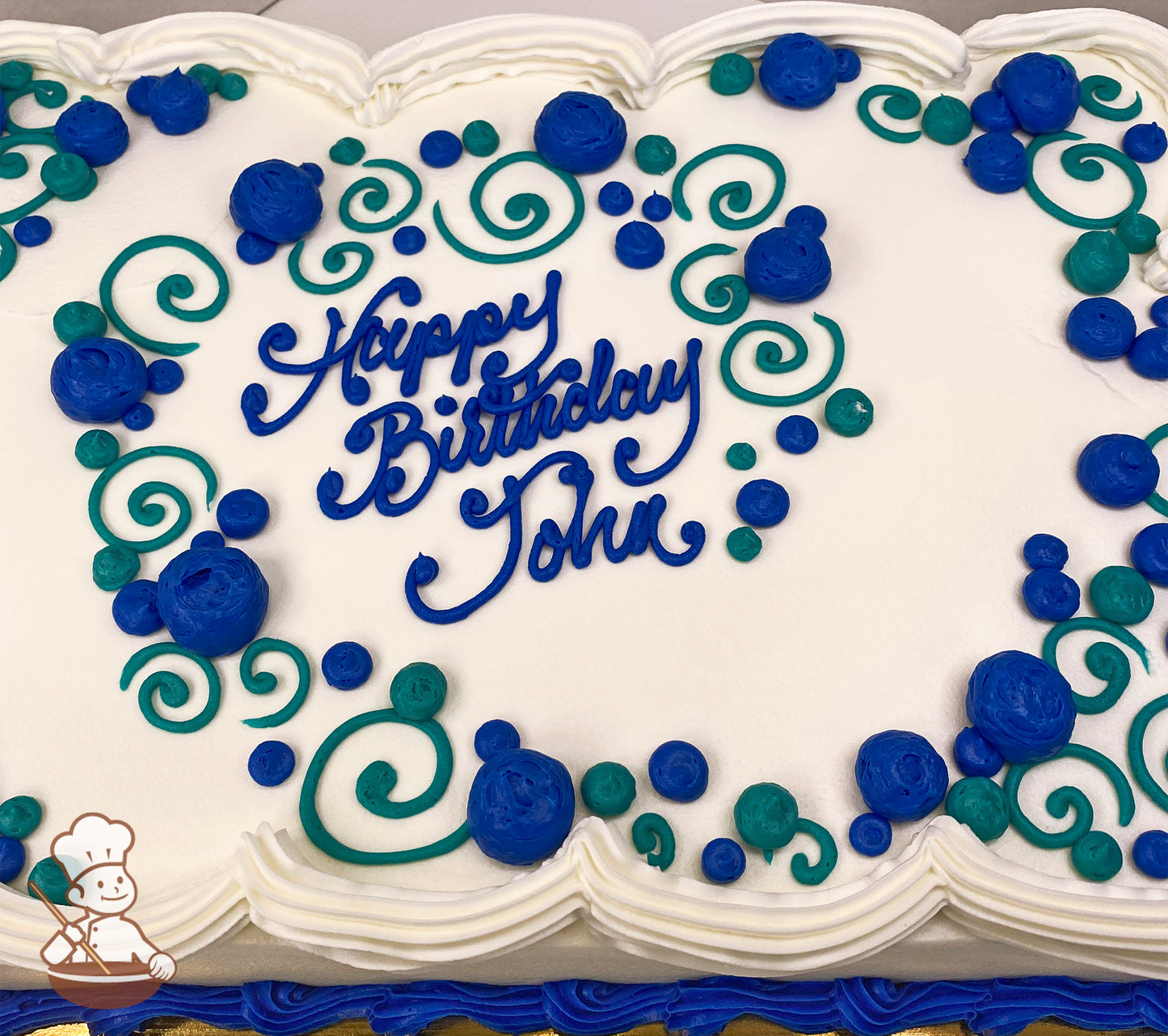 White sheet cake with blue and green buttercream swirls and dots. Scalloped white border.