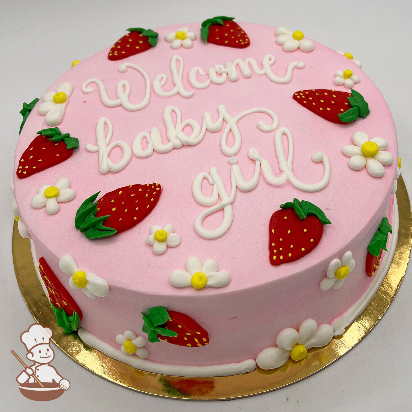 Round pink sheet cake with buttercream strawberries and daisies as decorations. Strawberries are red with green tops, and daisies are white with yellow centers.