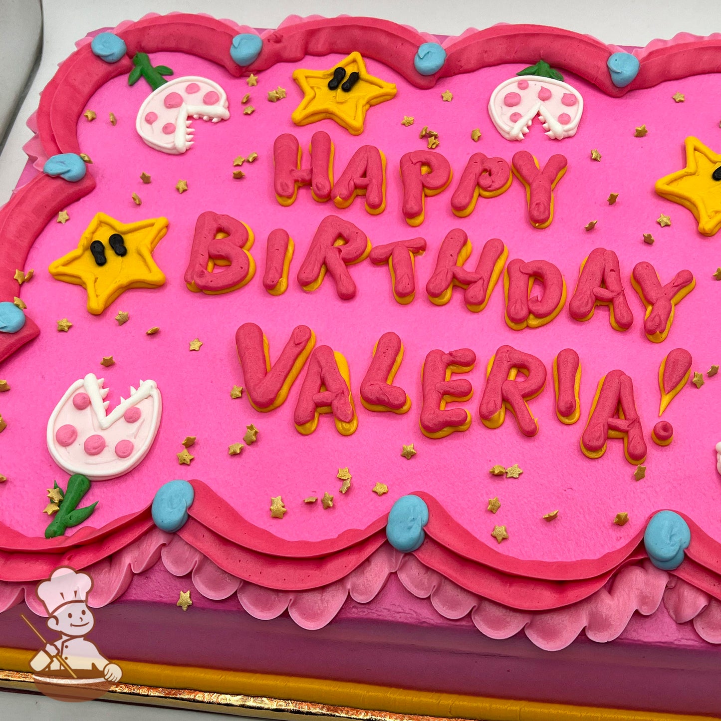 Pink sheet cake with buttercream stars, Piranha Plant decorations, and blue and pink dress trims.