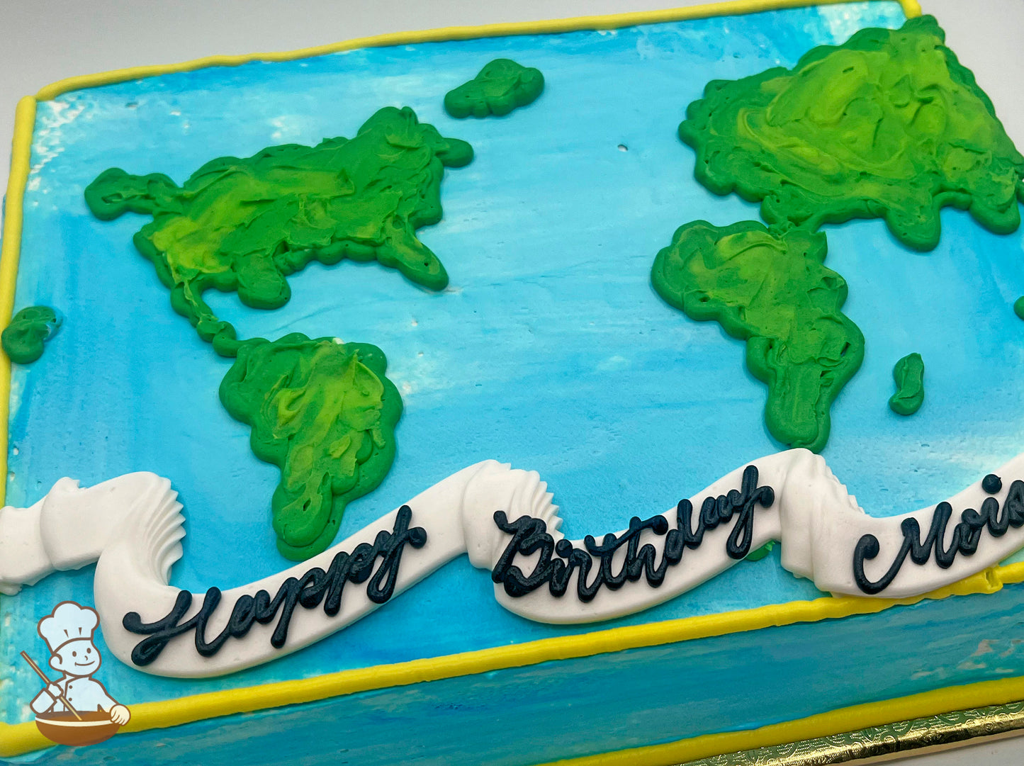 Sheet cake with blue frosting resembling an ocean, green continents shaped like a world map, and a white banner decoration at the bottom.