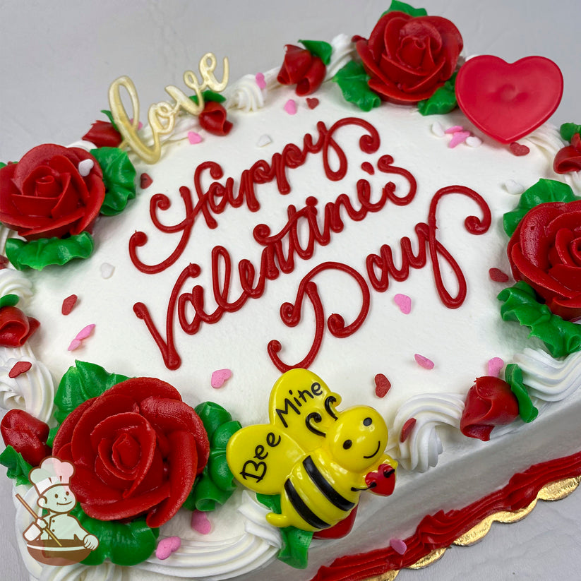 A white sheet cake decorated with red buttercream roses, green leaves, pink and red heart sprinkles, a red heart topper, and a yellow plastic bee with "Bee Mine" text.