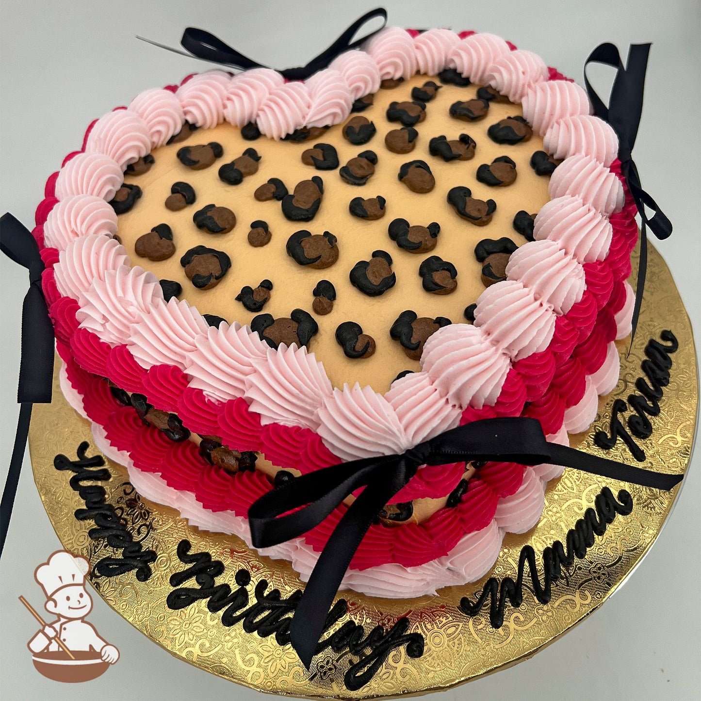 Heart-shaped sheet cake with cheetah print buttercream on top and sides, bordered by pink frosting, and decorated with black silk bows.