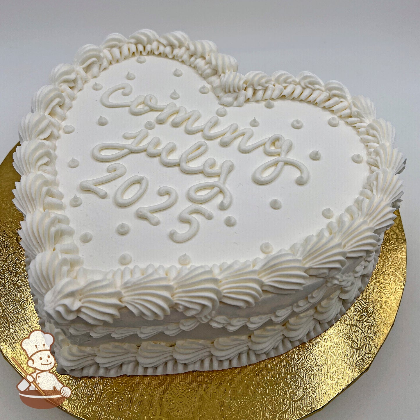 Heart-shaped white buttercream sheet cake, decorated with piped vintage-style swirls, Swiss dots, and a textured border, on a gold platter.