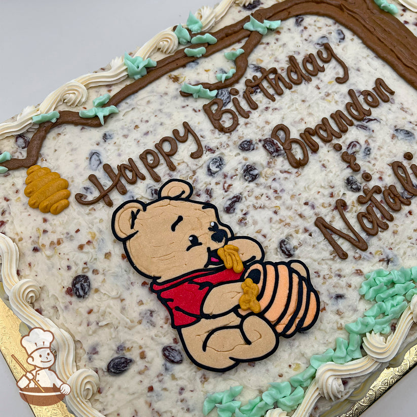Sheet cake with a textured frosting base, featuring Winnie the Pooh holding a honey pot, buttercream tree branches, honeycomb, and green leaf accents.