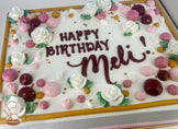 A sheet cake with white frosting, decorated with white buttercream roses, pink and burgundy dollops, gold pearl beads, and a gold border.
