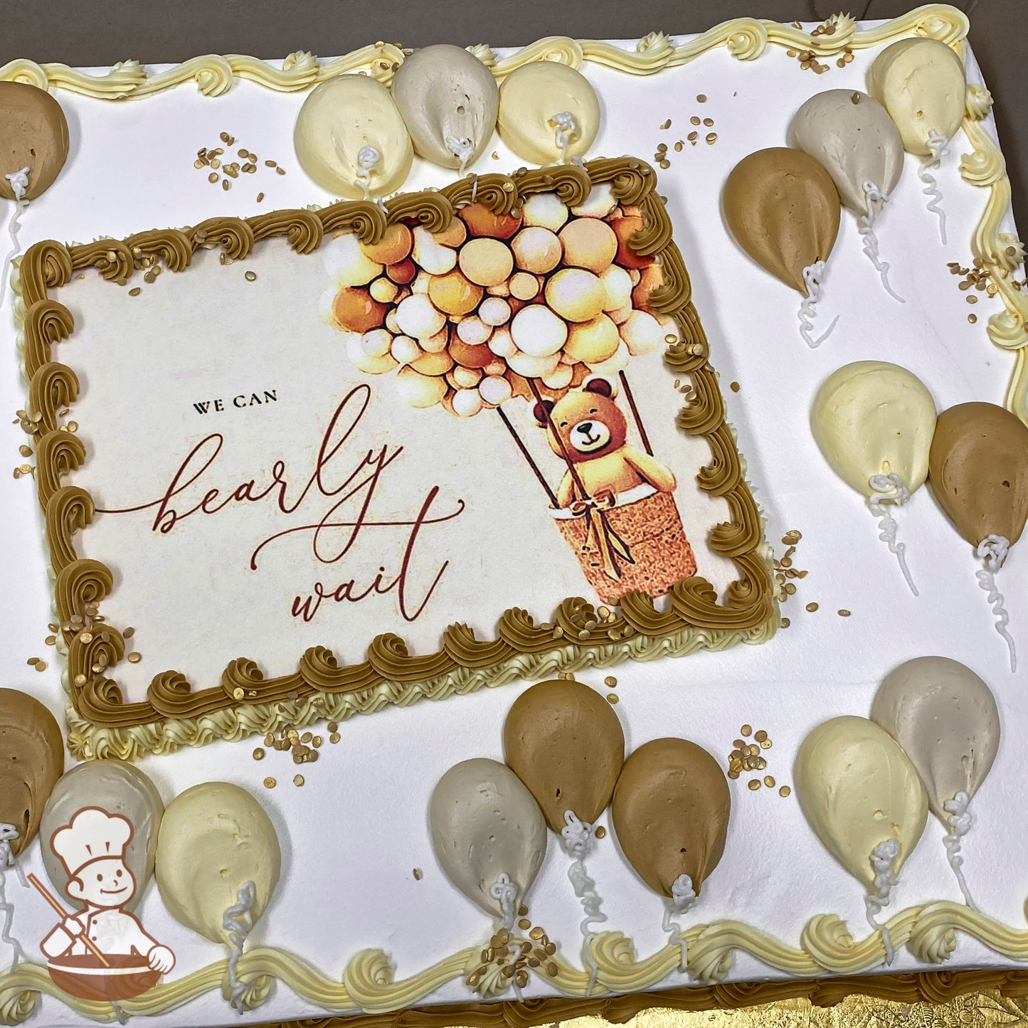 Sheet cake with white frosting, golden and cream buttercream balloons, gold sprinkles, and a printed photo layer framed by gold buttercream swirls.
