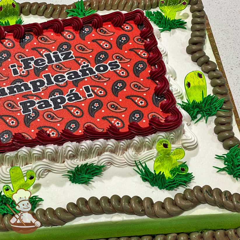 Sheet cake with buttercream decorations, featuring plastic cactus picks, green grass accents, and a brown rope-like trim around the edges.