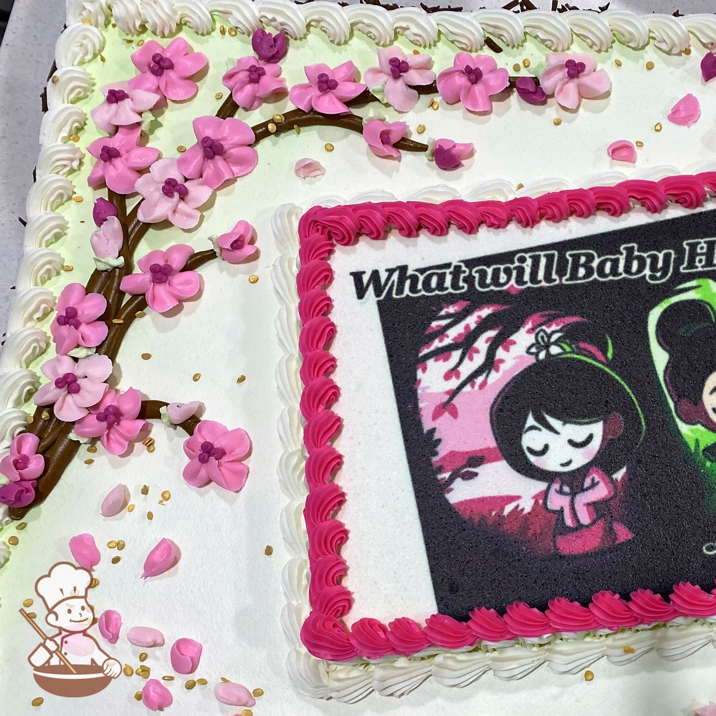 Sheet cake with white frosting, pink cherry blossom flowers and branches made of icing, scattered pink petals, and gold sprinkles.