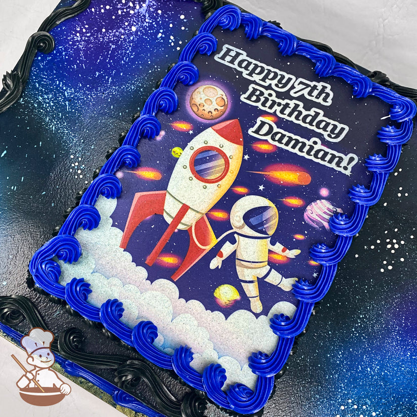 Sheet cake with a space theme, featuring blue and black buttercream swirls along the edges and a printed design bordered by bright blue piping.