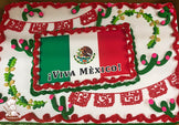 Sheet cake with red buttercream borders, green and pink cactus decorations, yellow and green vine accents, and red papel picado banner designs.