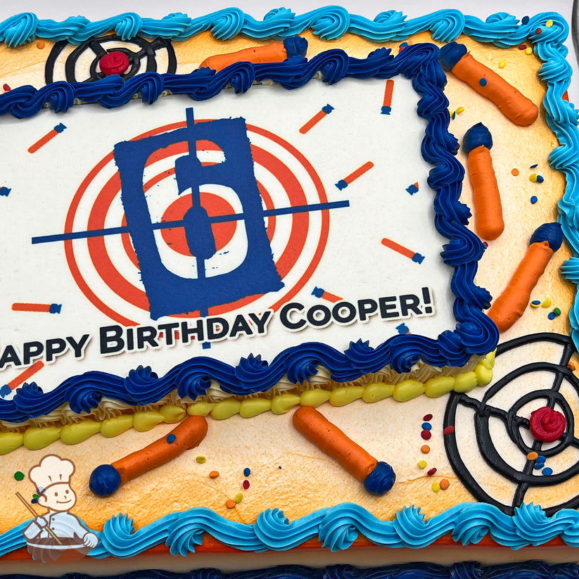 Sheet cake with blue and yellow buttercream borders, hand-piped Nerf darts, target designs, and colorful sprinkles as decorations.
