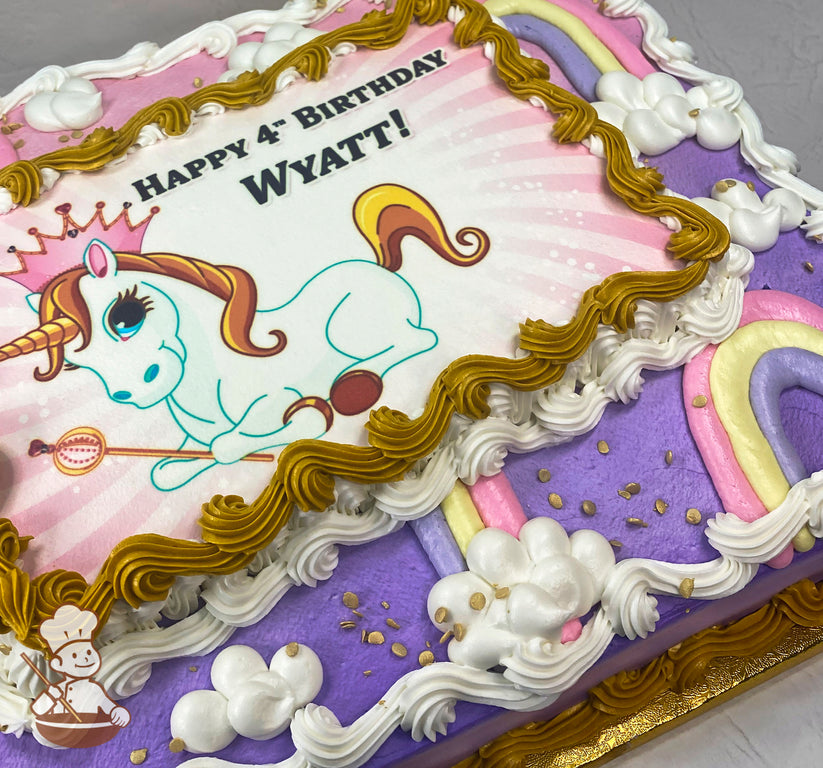 Sheet cake with purple base, hand-piped buttercream rainbows in pastel colors, white clouds, gold sprinkles, and golden and white frosting borders.