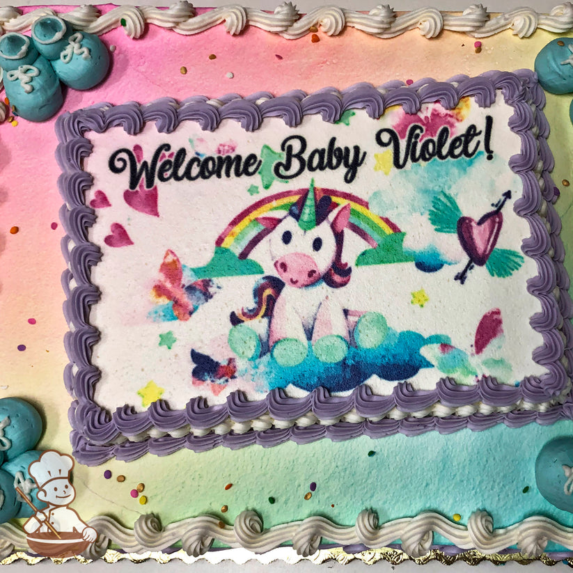 Sheet cake with pastel rainbow spray background, purple piped border, aqua buttercream baby booties, and colorful confetti accents.