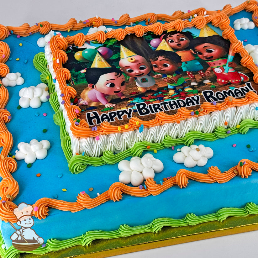 A rectangular sheet cake with blue frosting, orange and green piped borders, white buttercream clouds, and colorful sprinkles.