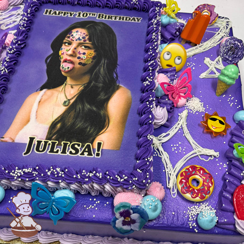 A purple sheet cake with piped buttercream borders, plastic butterflies, flowers, emoji decorations, a donut, ice cream cone, and white sprinkles.