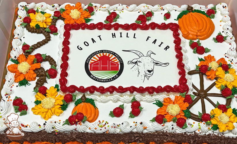 Sheet cake with buttercream decorations, featuring orange and yellow flowers, red swirls, and orange pumpkins. A brown wheel design is also present.