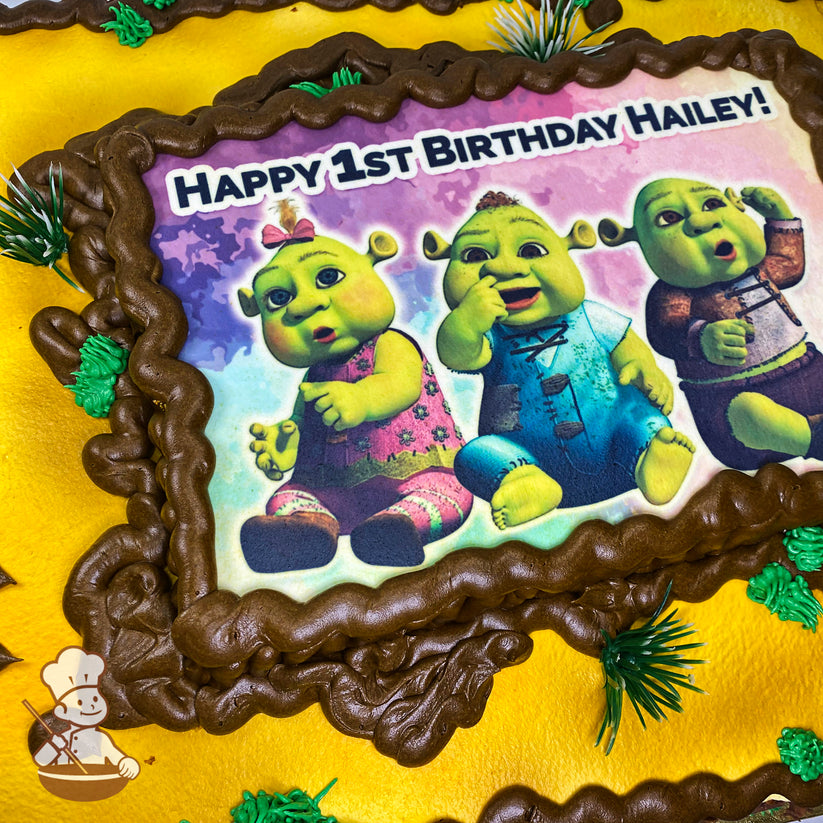 Sheet cake with a yellow base, brown borders, green grass-like accents, and a printed image in the center.
