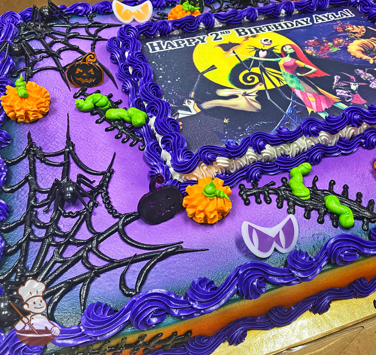 Purple and orange sheet cake with black spiderwebs, plastic spiders, orange pumpkins, and purple buttercream borders.