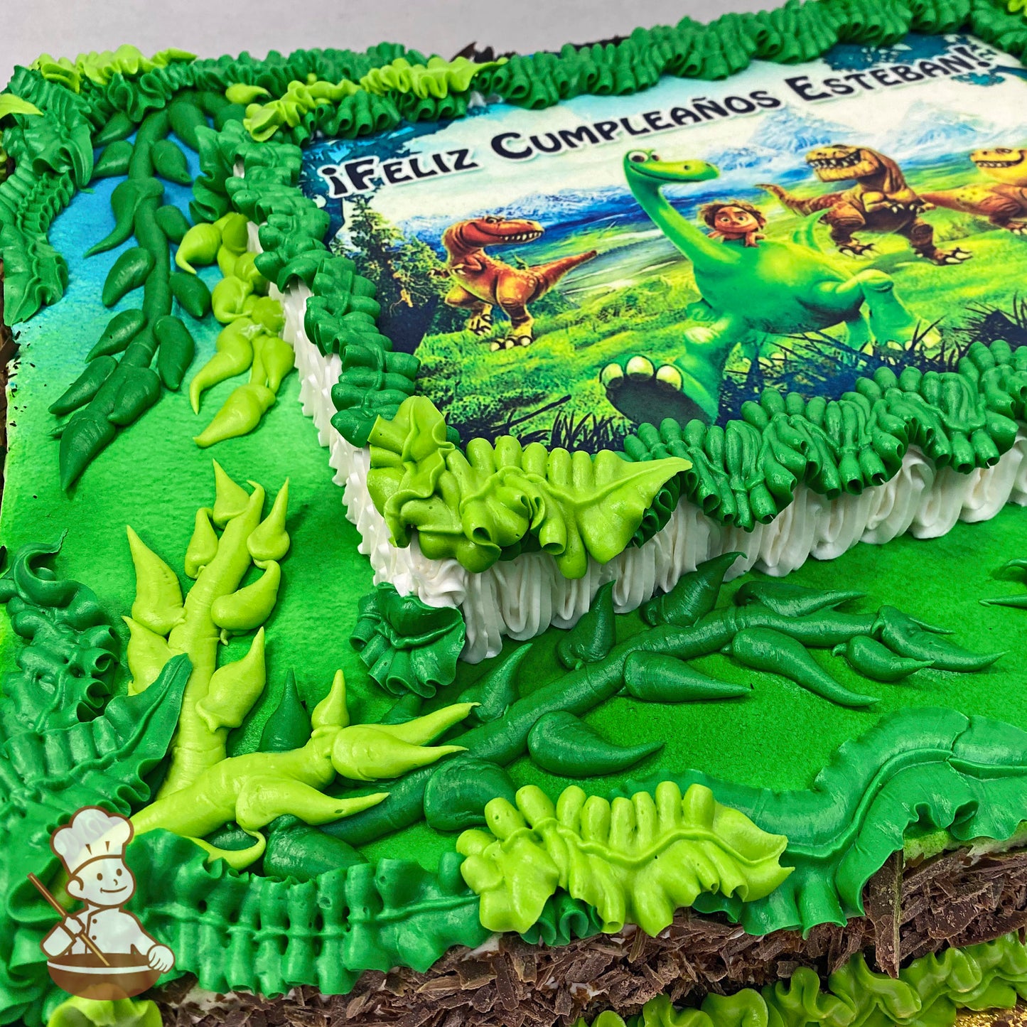Sheet cake with vibrant green buttercream jungle vines and leaves decorating the edges and corners. A printed image is centered on the cake.
