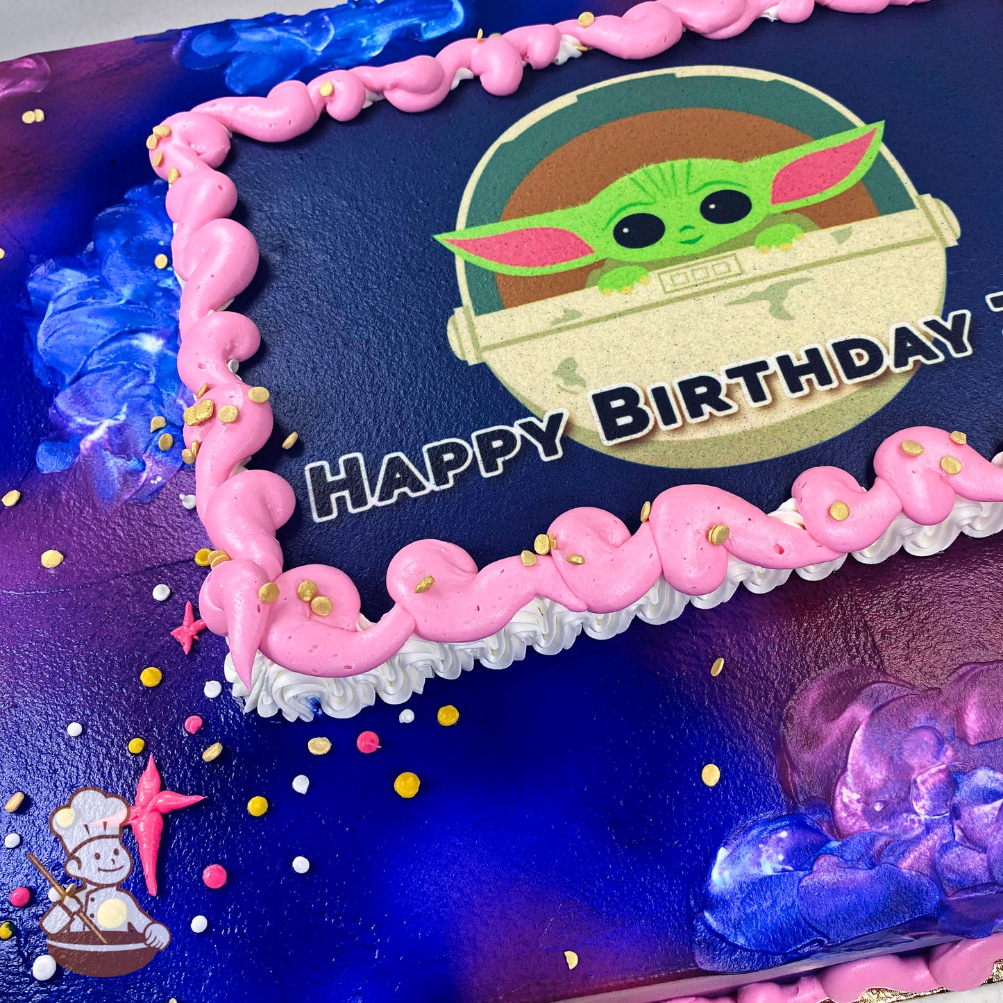Sheet cake with a dark blue and purple background, decorated with pink buttercream swirl trims, gold confetti sprinkles, and small star accents.