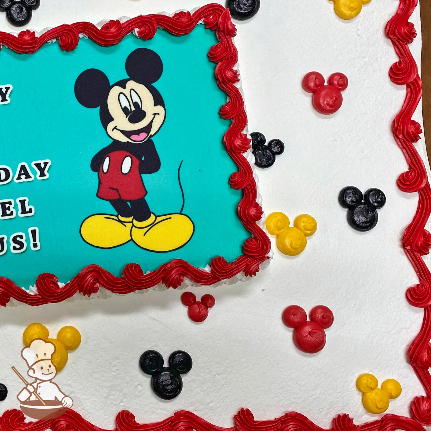 Sheet cake with a printed Mickey Mouse image, red buttercream border, and scattered red, yellow, and black Mickey-shaped buttercream decorations.