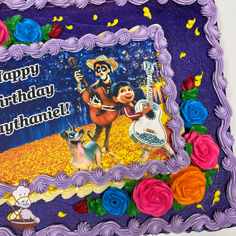 Purple sheet cake with colorful buttercream roses in pink, blue, and orange at the corners. Yellow accents and a printed image in the center.
