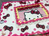 Sheet cake with pink and white buttercream borders, red and black Hello Kitty bows, small Hello Kitty faces, and pink buttercream dots.