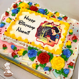 Sheet cake with buttercream roses in red, yellow, and blue, green leaves, white and yellow swirl borders, and red heart sprinkles around the edges.