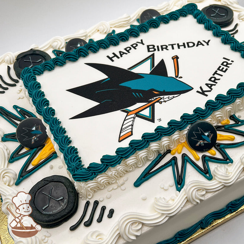 Sheet cake with teal and white buttercream borders, San Jose Sharks logo-themed plastic hockey puck decorations, and teal and yellow starburst designs.