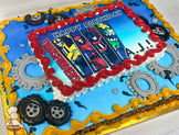 Sheet cake with a blue base, red and yellow piped borders, gray gear decorations, and black piped tires around the edges.