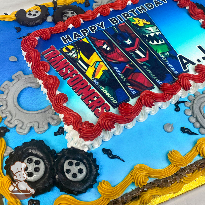 Sheet cake with a blue base, red and yellow piped borders, gray gear decorations, and black piped tires around the edges.