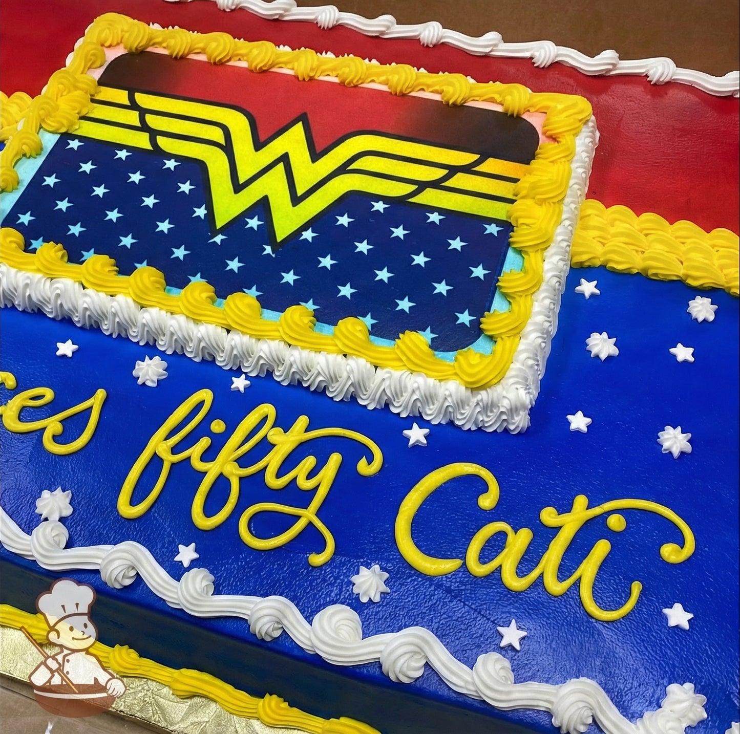 Sheet cake with a printed Wonder Woman logo, yellow and white buttercream borders, blue frosting with white star piping's, and red accents.