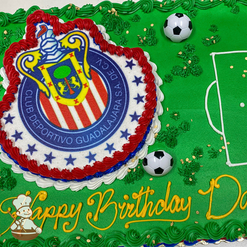 Sheet cake with green frosting resembling a soccer field, featuring a Guadalajara Chivas logo cutout bordered in red, white, and blue, plastic soccer balls, and piped grass accents.