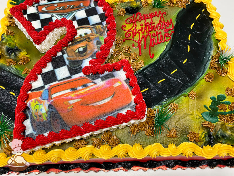 Sheet cake with a large number 2 cutout featuring Lightning McQueen and Mater. Decorated with buttercream road, cacti, bushes, and yellow border.
