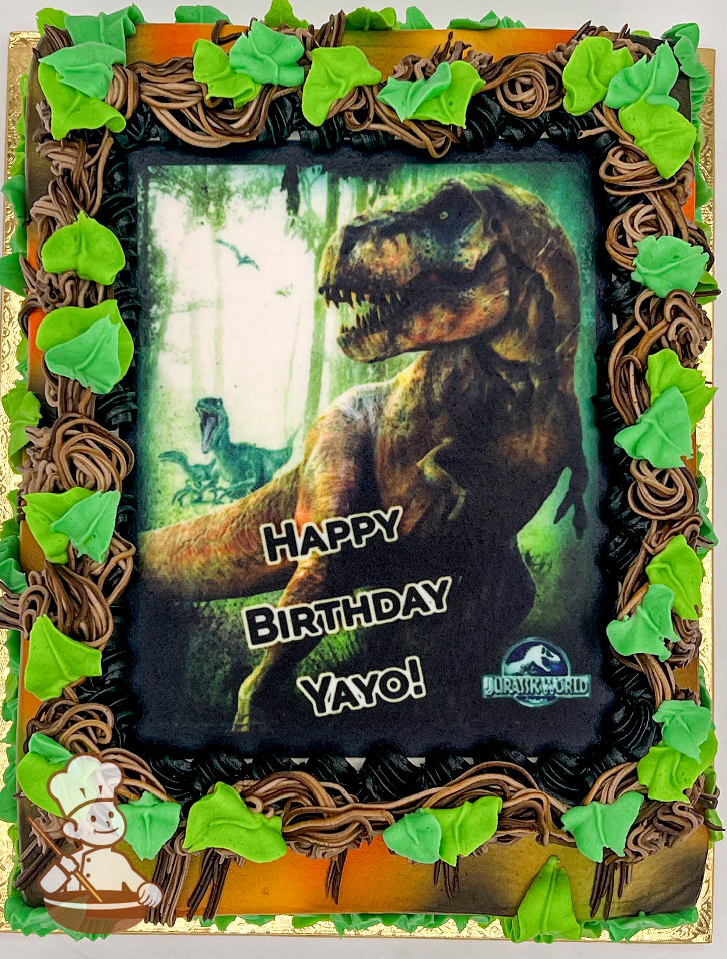 Sheet cake with jungle theme, featuring buttercream vines and green leaves around a printed photo layer.