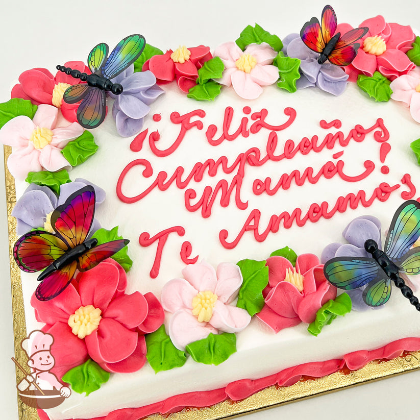 Sheet cake with colorful buttercream flowers in pink, purple, green leaves, and plastic butterfly and dragonfly decorations on a gold base.