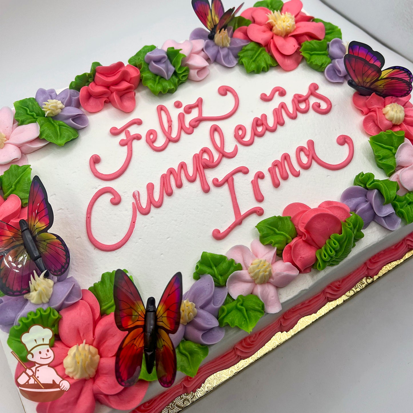 Sheet cake with white frosting, decorated with pink, purple, and light red buttercream flowers, green leaves, and translucent plastic butterfly toppers.