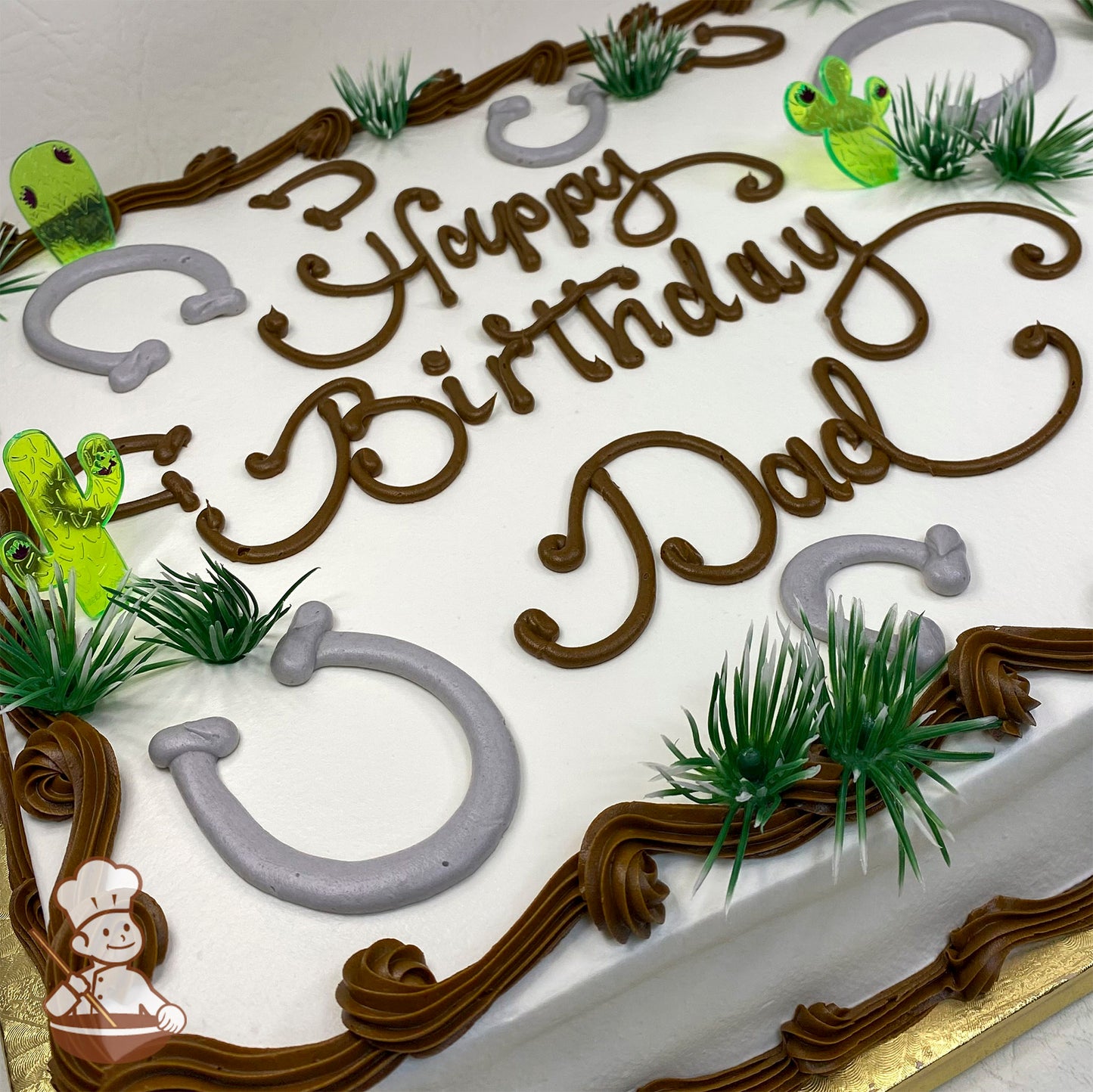 Sheet cake with buttercream horseshoes, plastic cactus rings, and green bushes. Brown icing borders decorate the edges.