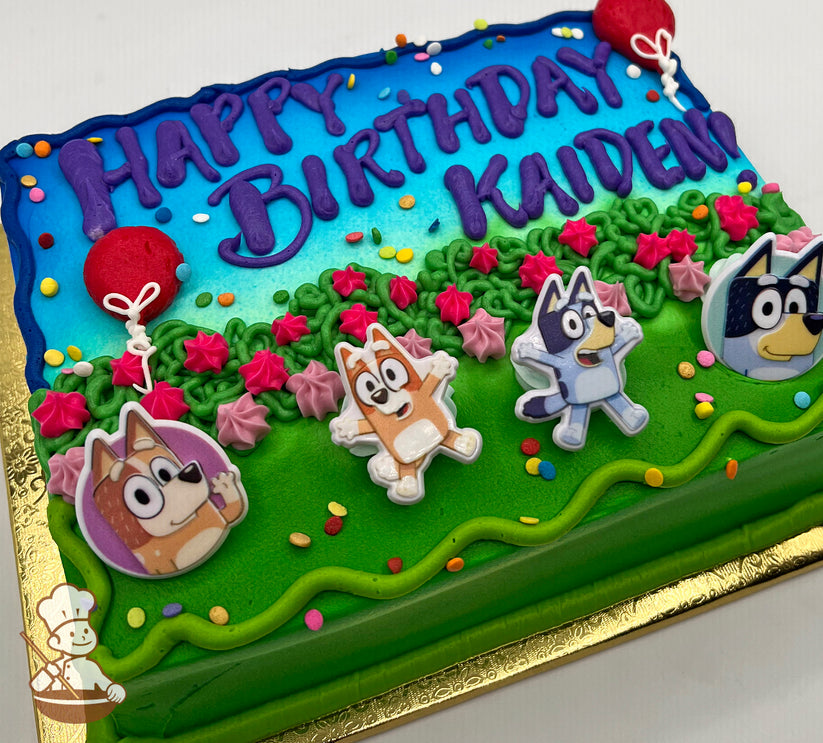 Sheet cake with a blue and green design, featuring plastic Bluey character toppers, pink and green floral accents, and colorful sprinkles.