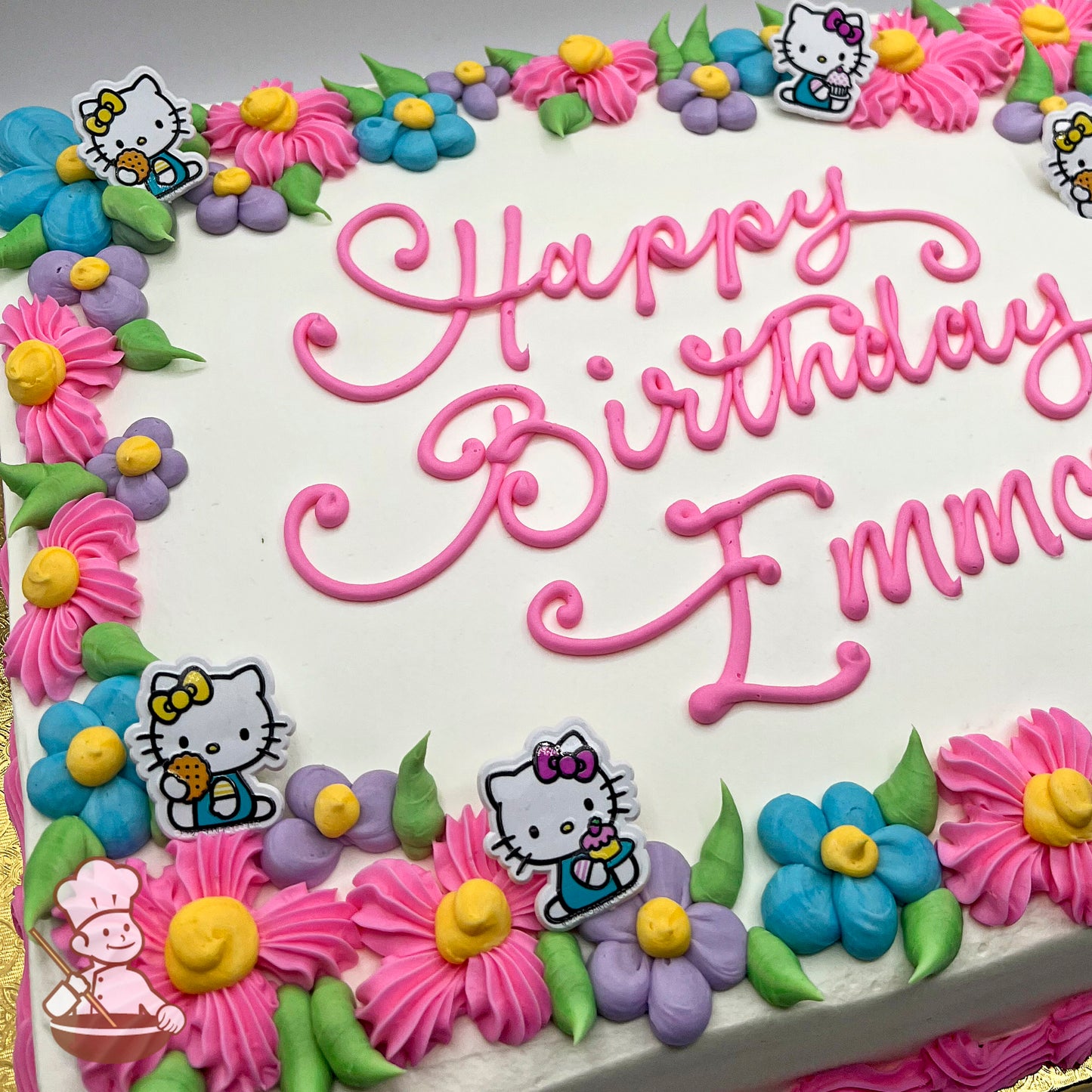 Sheet cake with white frosting, pink piped border, colorful daisies in pink, blue, and purple, and plastic Hello Kitty toppers holding treats.