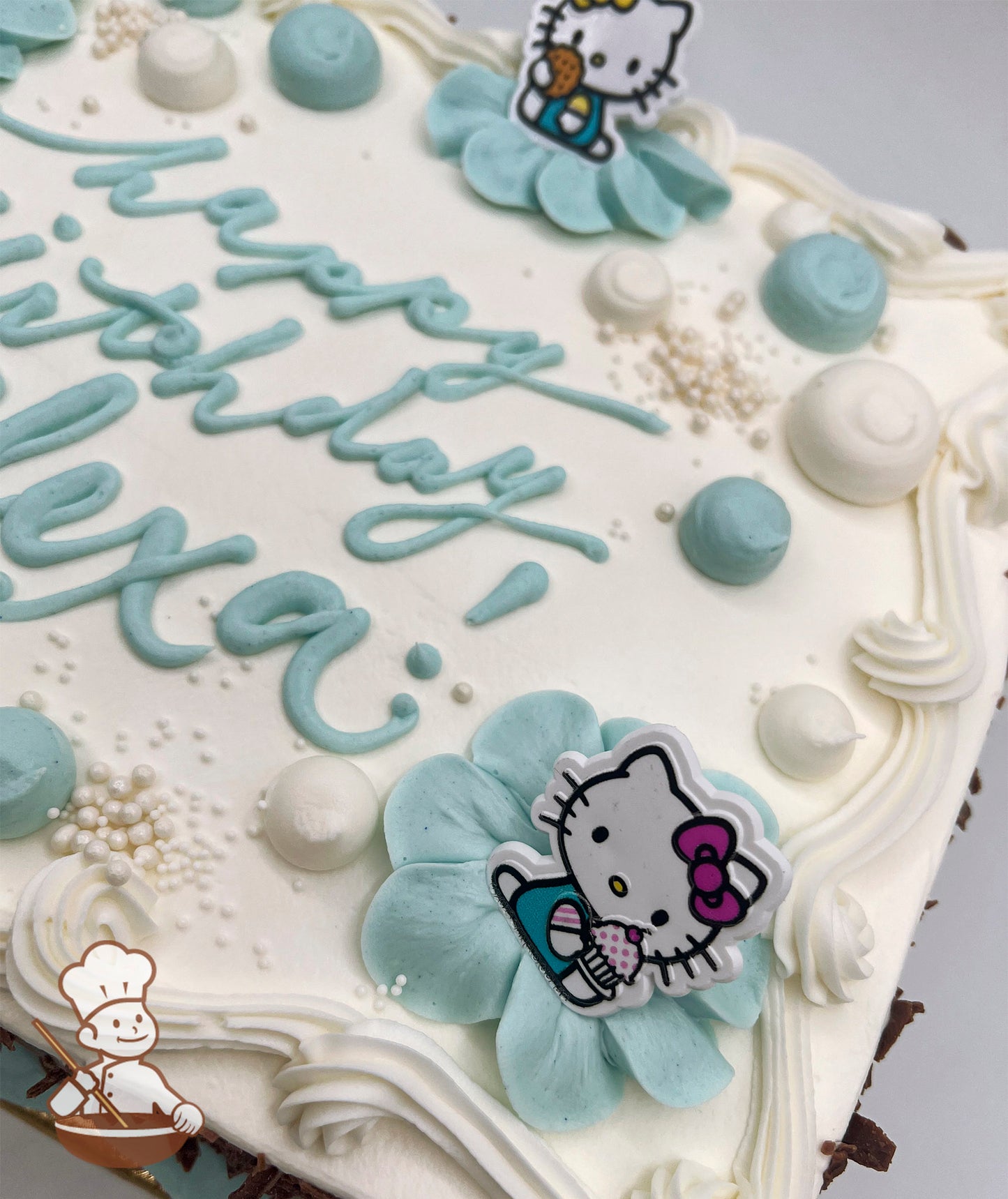 Sheet cake with buttercream petals, blue and white dollops, pearl sprinkles, and plastic Hello Kitty toys with swirl trims.