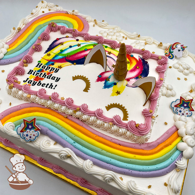 Sheet cake with buttercream rainbow roads, plastic unicorn horn and ears, gold star sprinkles, and rainbow star rings. Plastic unicorn toy on top.