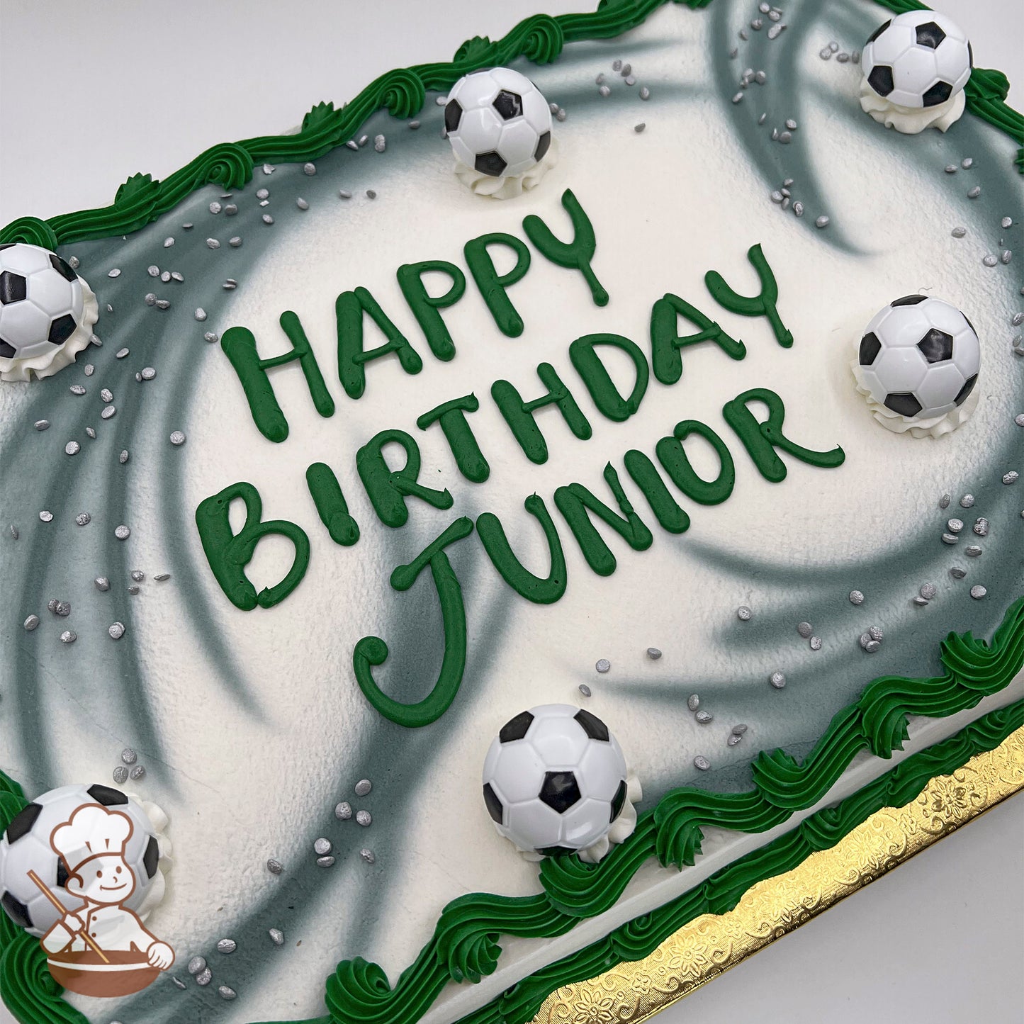 Sheet cake with gray decoration, green piped borders, silver sprinkles, and plastic soccer ball decorations.