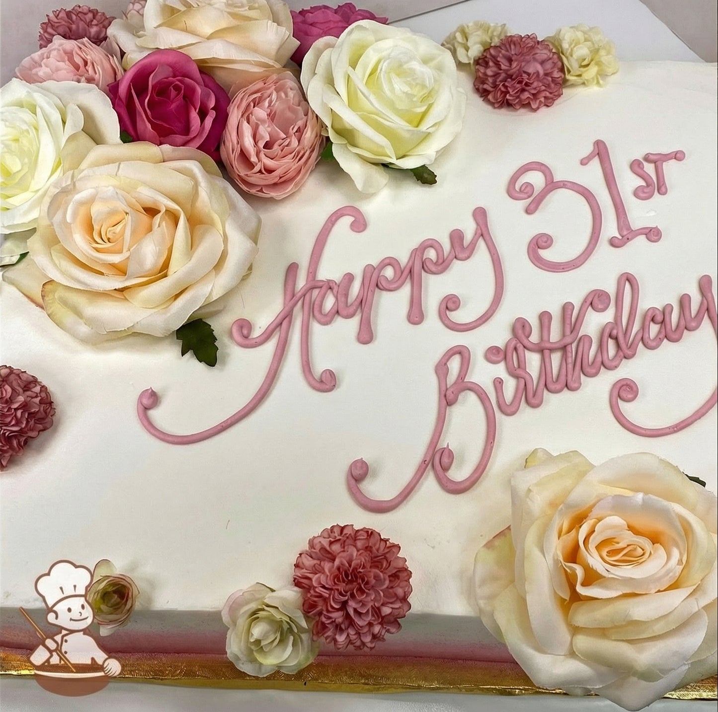 Sheet cake with white frosting, decorated with pink, peach, white roses, and pink carnations, arranged in clusters.